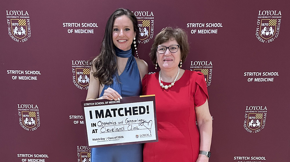 Megi Maci holding a sign that says where she matched with her mom next to her